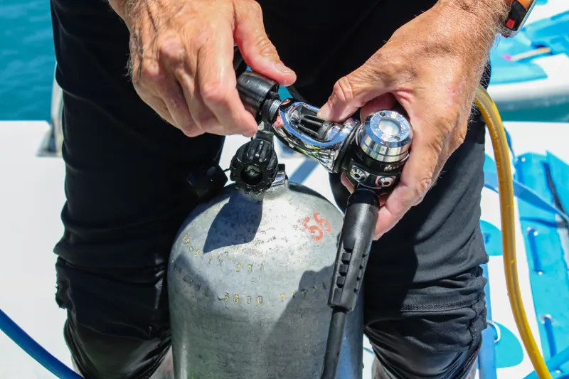 Hands fitting a regulator onto a scuba cylinder