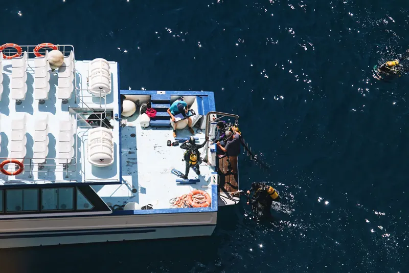 Aerial view of a dive boat with divers entering the water