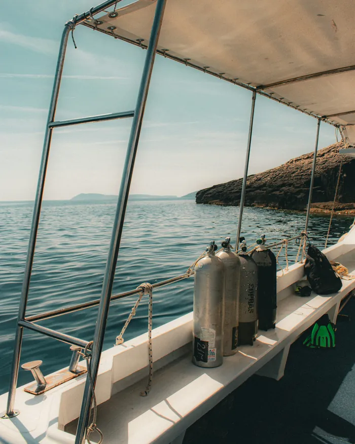 Scuba cylinders secured along the rail of a dive boat, ready for the first dive, with the coast behind